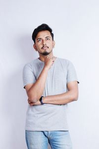 Portrait of young man standing against white background