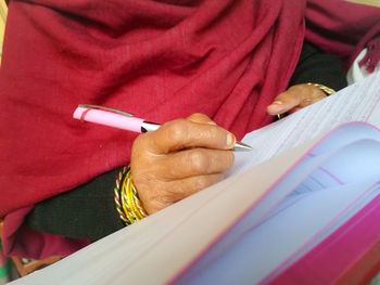 Midsection of woman writing in book