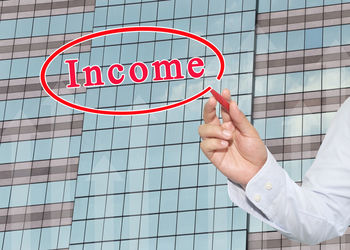 Low section of person holding glass sign against building