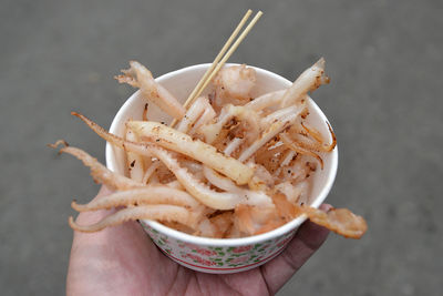 Cropped hand holding fried cuttlefish in bowl