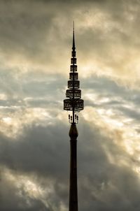 Low angle view of communications tower against cloudy sky