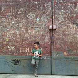 Boy standing against rusty wall