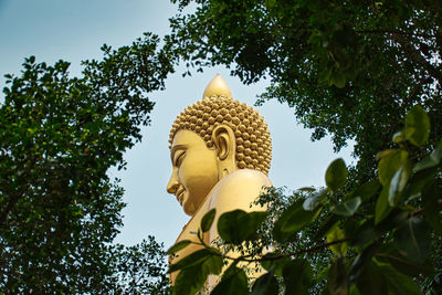 Low angle view of statue by trees against sky