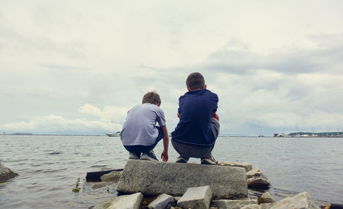 Rear view of men looking at sea against sky
