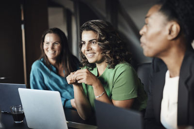 Smiling businesswoman with female colleagues during meeting at office