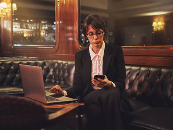 Young woman using mobile phone while sitting on table