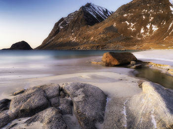 Rocks on beach against sky during sunset