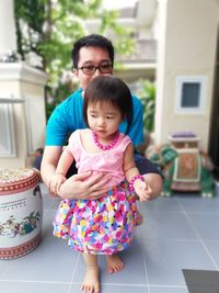 Portrait of father holding girl on tiled floor