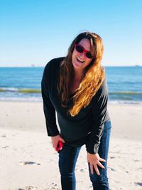 Portrait of happy mature woman wearing sunglasses at beach