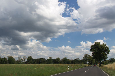 Road by trees against sky