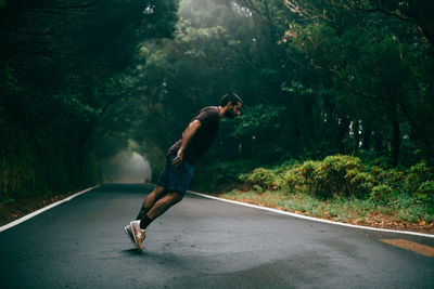 Man jumping on road amidst trees