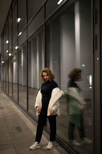 Full length portrait of woman on sidewalk in city