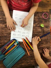 High angle view of mother and girl holding pencils on table
