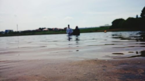 Silhouette people in river against sky