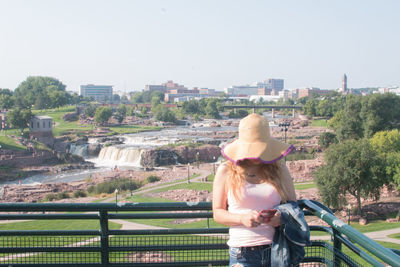 Rear view of woman looking at cityscape against sky