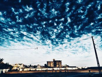 Low angle view of crane against cloudy sky
