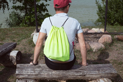 Rear view of man sitting on seat against lake