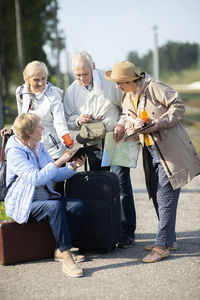 Group of positive senior people looking at map on traveling journey during pandemic covid-19 