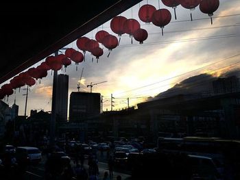 Low angle view of lanterns hanging against sky at sunset