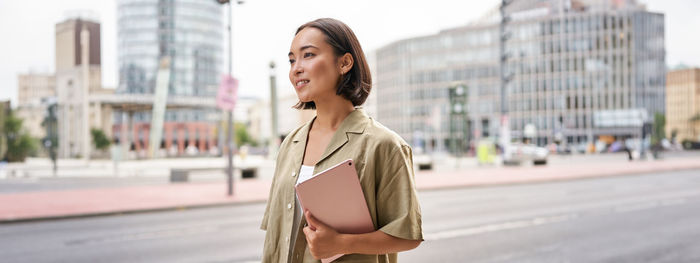 Portrait of young woman standing in city