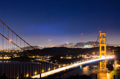 Illuminated suspension bridge over river at night