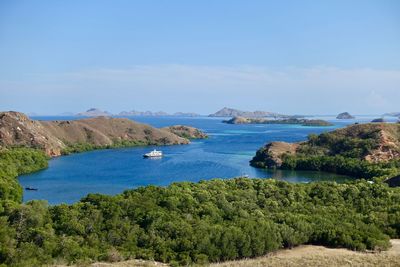 Boat moored in a tranquil bay, komodo indonesia. blue water and islands visible in the distance.