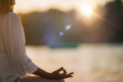 Sungazing. woman meditating by the lake, sitting in lotus position.