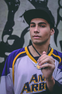 Portrait of man standing against graffiti wall