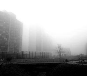 Buildings in city against sky in foggy weather