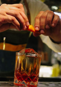 Close-up of hand making  negroni drink on table