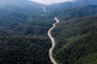 Long road curved in valley connecting countryside in the rainforest and the verdant hill forest 