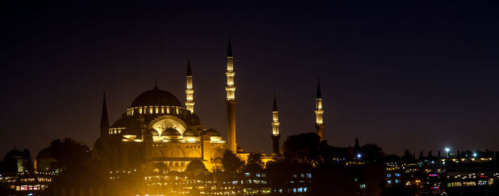 Illuminated buildings in city against sky at night