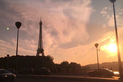 Car on bridge with eiffel tower against cloudy sky at sunset