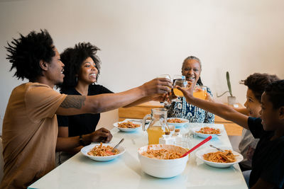 Family toasting drinks while sitting at dining table