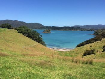 Scenic view of landscape and sea against clear blue sky