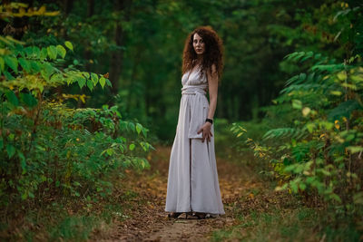 Woman standing by tree in forest