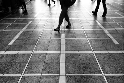 Low section of people walking on tiled floor