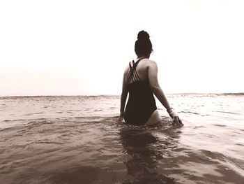 Rear view of woman in sea against clear sky