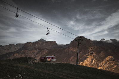 Overhead cable car over mountains against sky