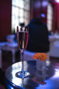 Close-up of champagne flute with flower vase on table in restaurant