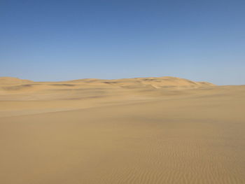 Scenic view of desert against clear blue sky