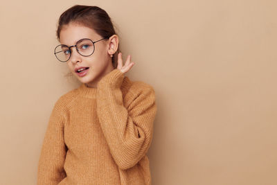 Portrait of girl in eyeglasses against beige background