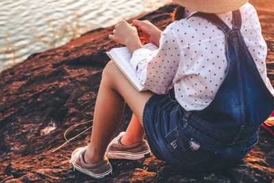 Low section of women sitting on rock