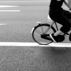 Low section of man riding bicycle on road