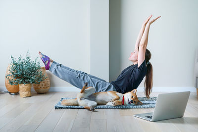Doga is the practice of yoga as exercise with dogs. woman in yoga position balancing with her dog.