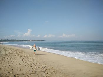 Surfer standing at beach against sky