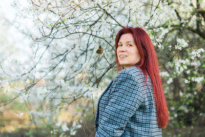 Portrait of young woman standing against trees