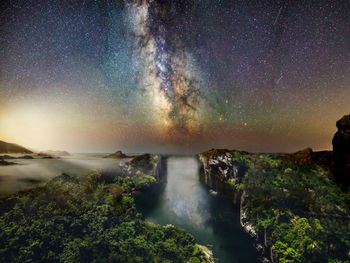 Scenic view of waterfall against sky at night