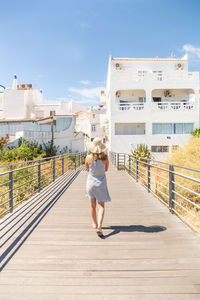 Rear view full length of woman walking on footbridge