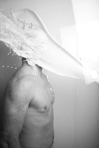 Milk splashing over shirtless man standing in bathroom